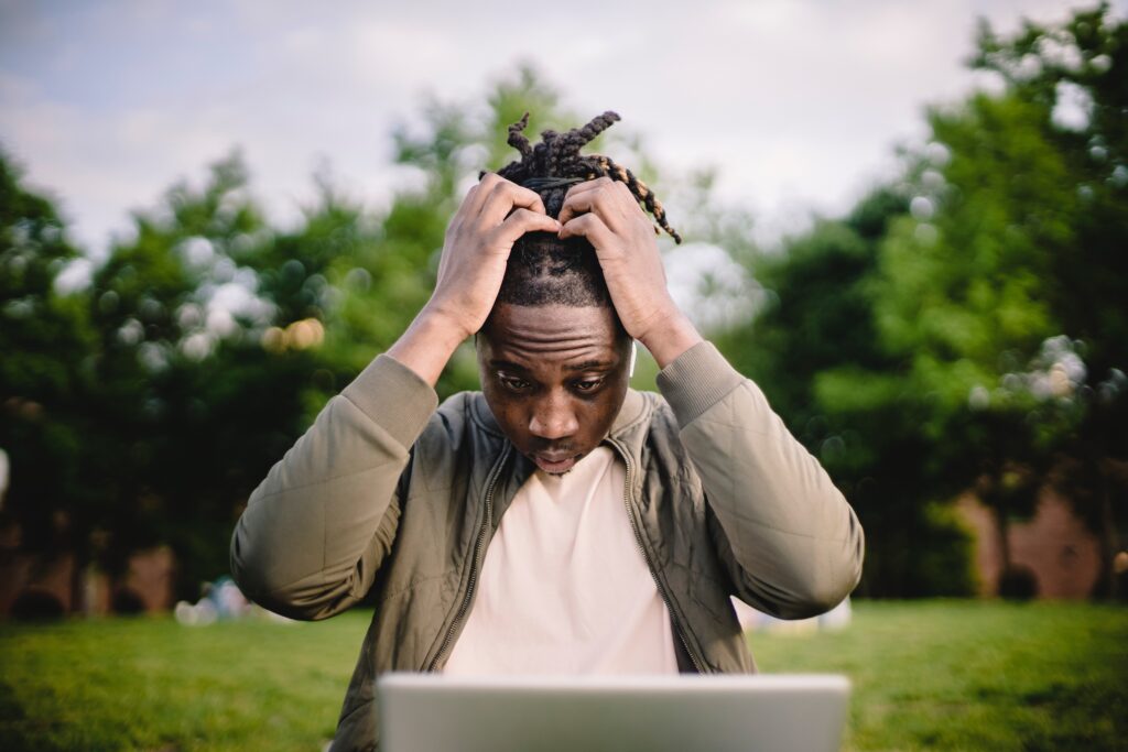 A man with both of his hands brought to his head, looking distressed